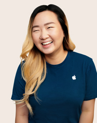 Apple Retail employee with long hair, smiling at the camera.