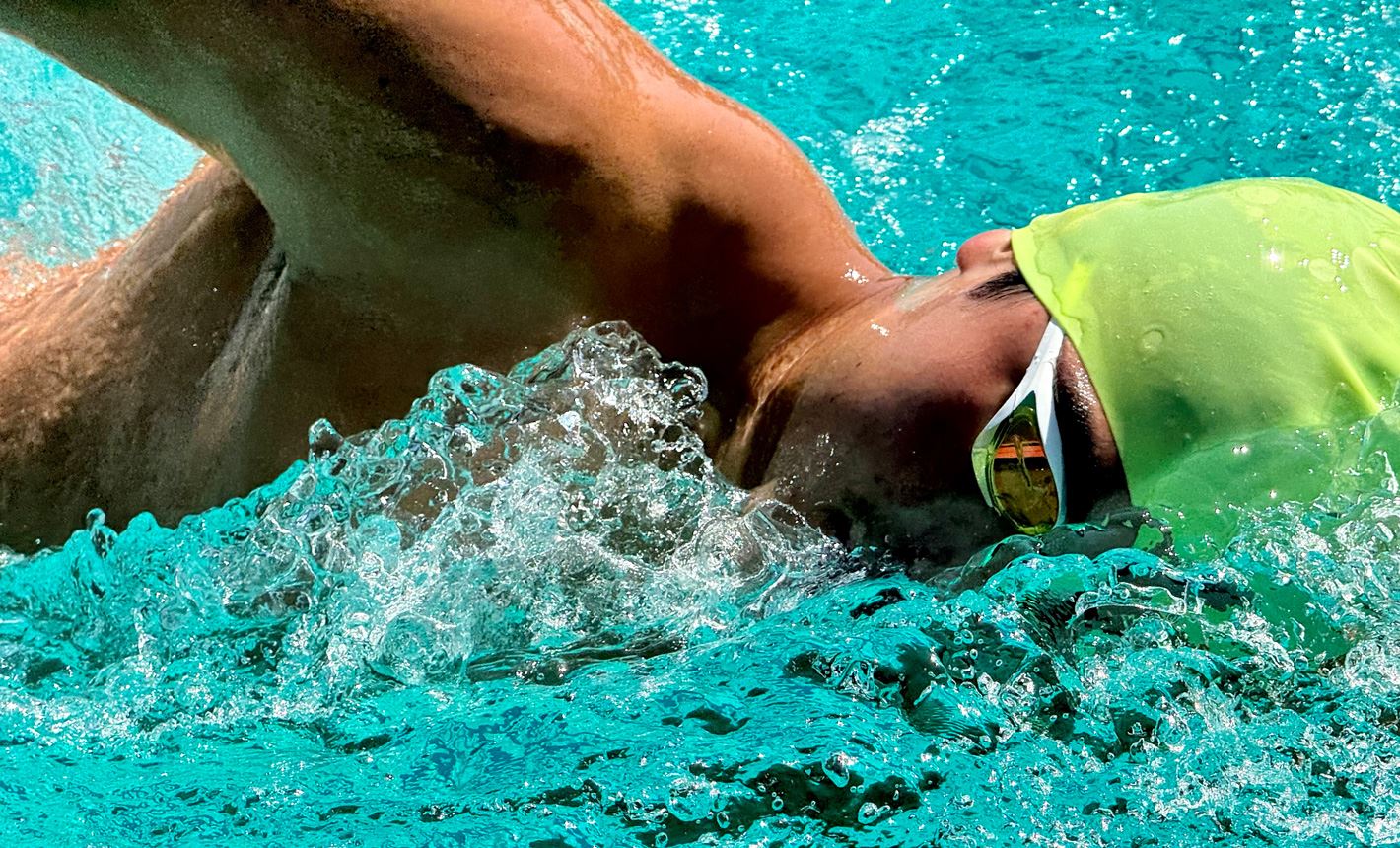 A very detailed, zoomed in shot of a swimmer in a pool with water splashing around him