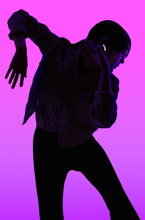 Silhouette of a person dancing with left arm angled down and right arm angled up, face is backlit in purple to highlight AirPods fitting securely in right ear.