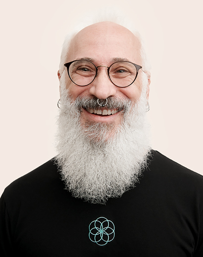 Apple Retail employee with a white beard, smiling at the camera.